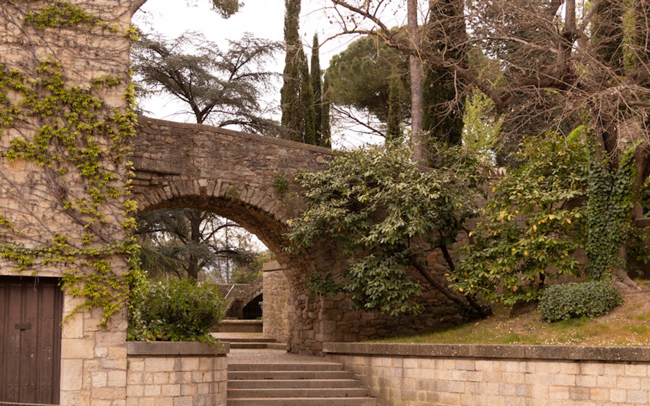 Stone archway and steps surrounded by greenery at Arab Baths in Girona.