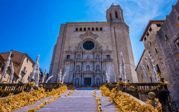 Cathedral of Girona facade with floral decorations on steps.