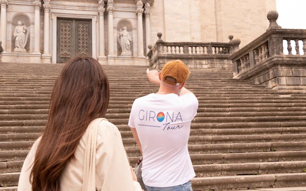 Tour guide leading visitors up steps to Girona Cathedral entrance.