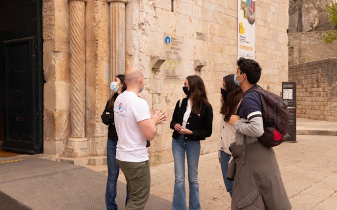 Tour guide explaining historical site to group in Girona, Spain.