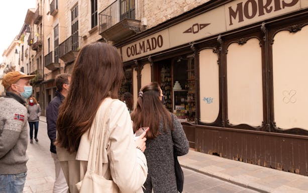 Tourists exploring a historic street in medieval Girona, Spain.