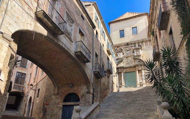 Medieval stone archway and steps in Girona, Spain, leading to historic buildings.