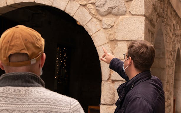 Guide pointing at medieval stone archway in Girona tour.
