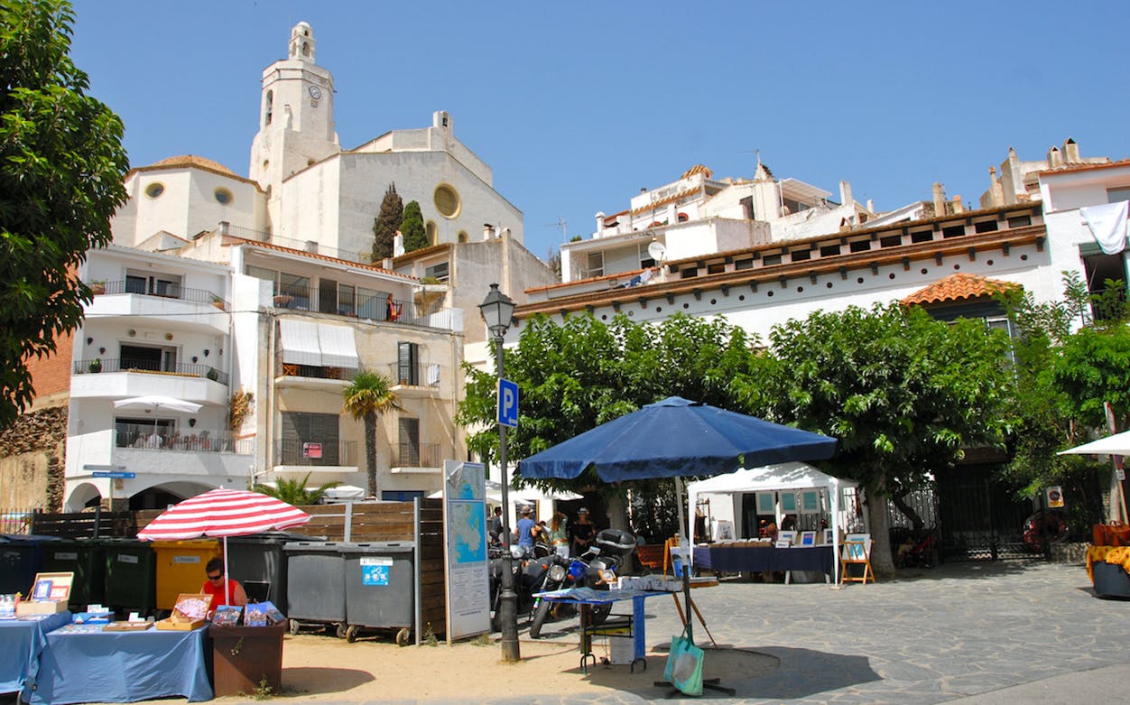 Cadaqués town square with market stalls and historic church in the background.