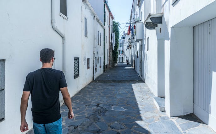 Narrow street in Cadaqués with whitewashed buildings, part of the boat trip tour from Roses.