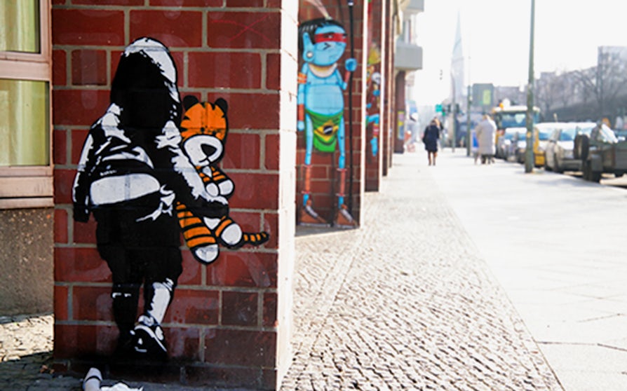 Street art on a Berlin wall featuring a child with a stuffed tiger during a guided tour.