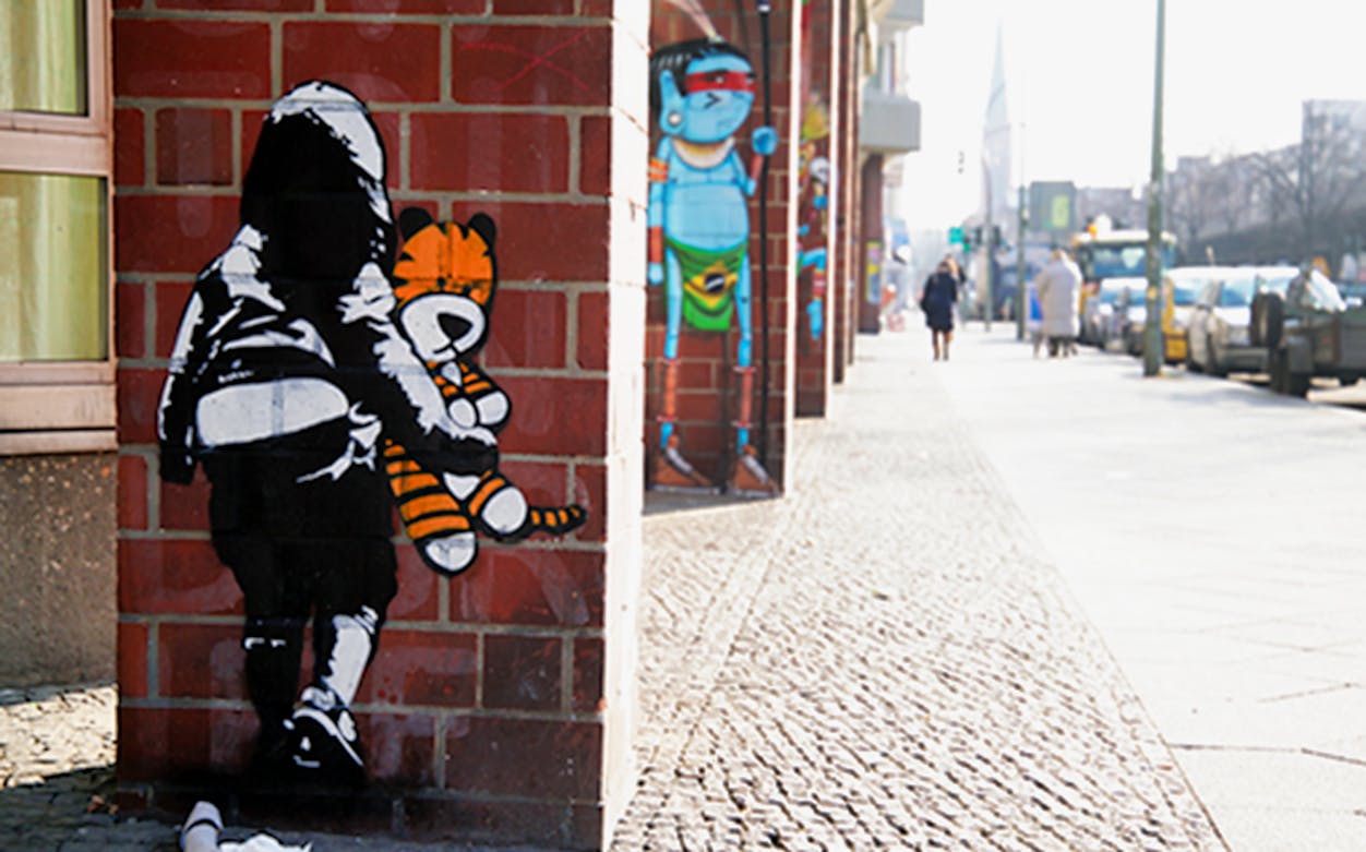 Street art on a Berlin wall featuring a child with a stuffed tiger during a guided tour.