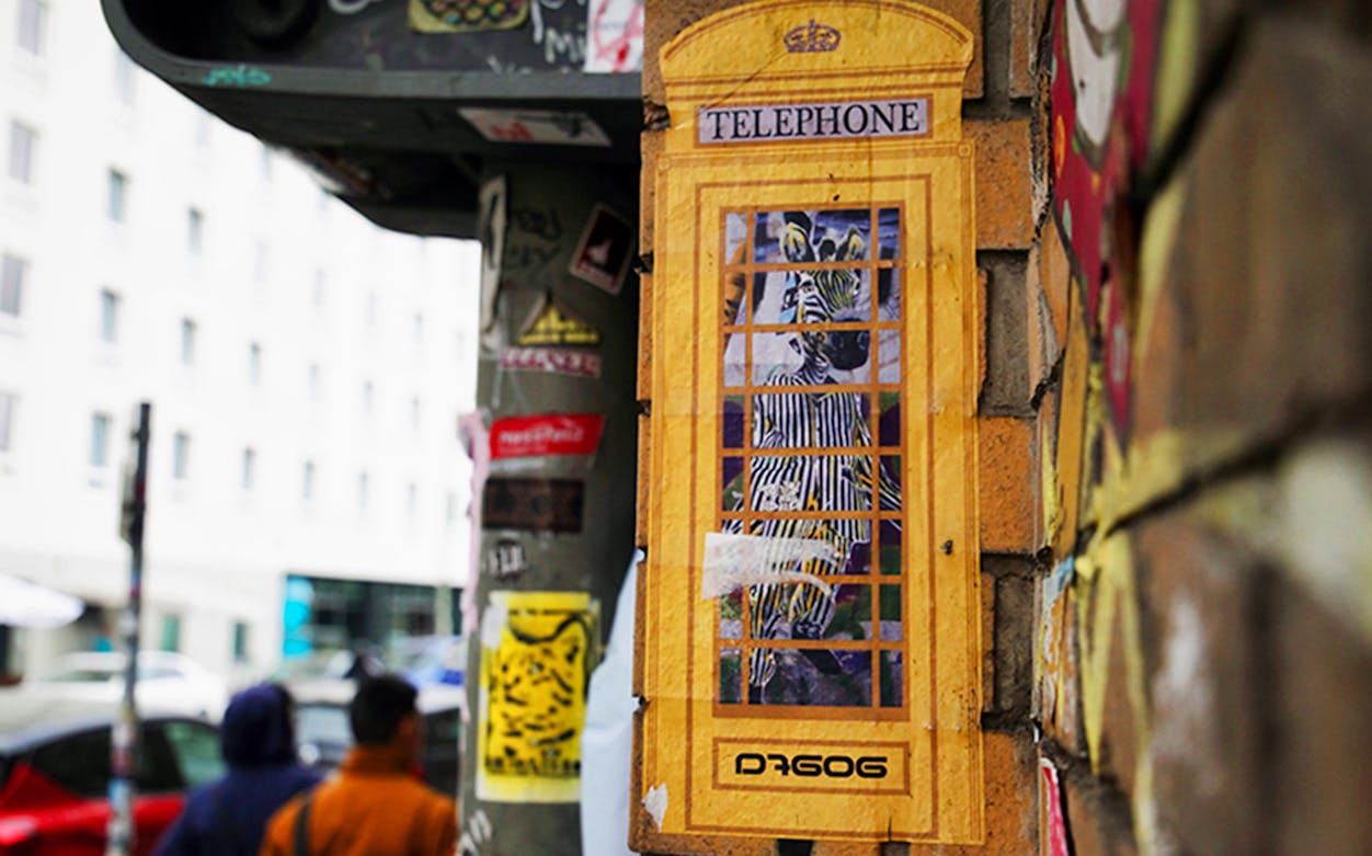 Street art of a zebra in a yellow phone booth on a Berlin wall during a guided tour.