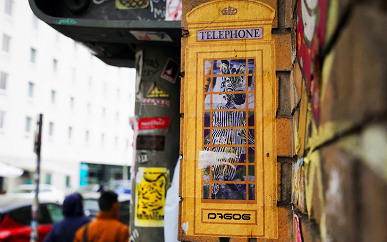 Street art of a zebra in a yellow phone booth on a Berlin wall during a guided tour.
