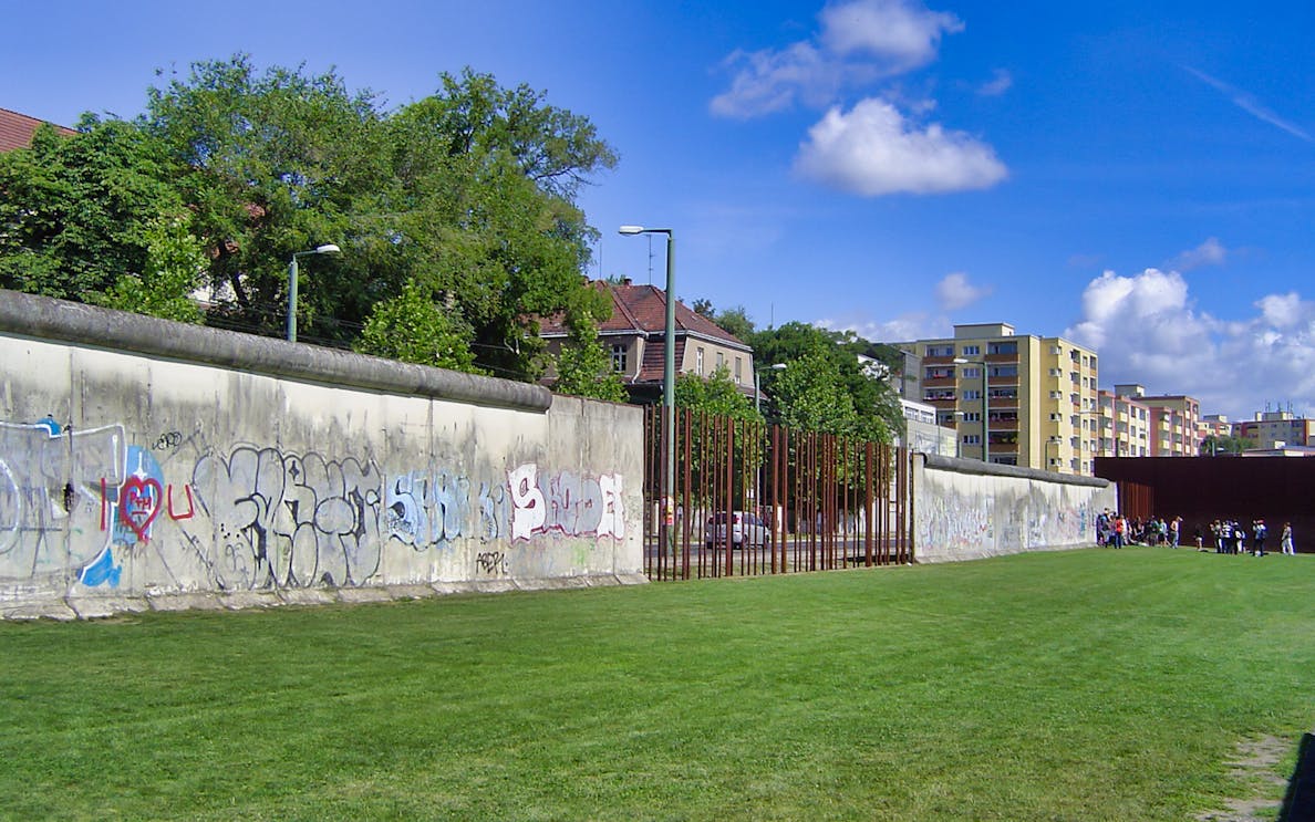 Berlin Wall with graffiti and nearby buildings on Cold War walking tour.
