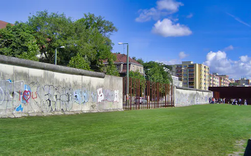 Berlin Wall with graffiti and nearby buildings on Cold War walking tour.