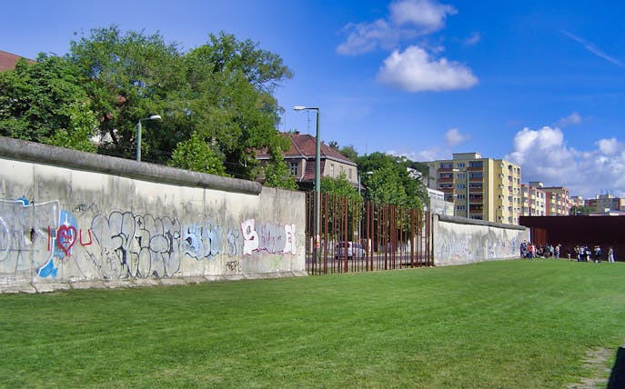 Berlin Wall with graffiti and nearby buildings on Cold War walking tour.