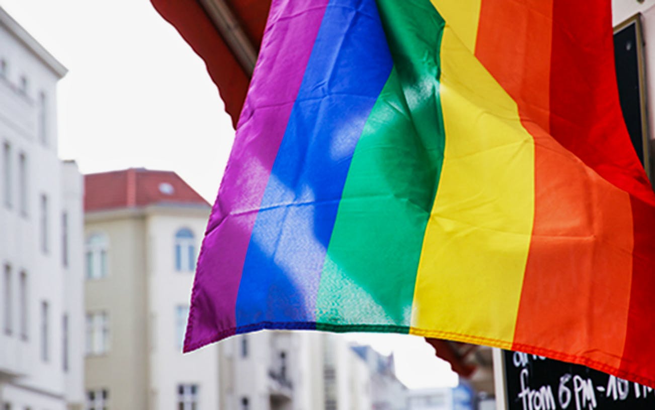 Rainbow flag waving in Berlin street, symbolizing LGBTIQ culture for walking tour.