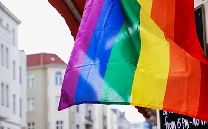 Rainbow flag waving in Berlin street, symbolizing LGBTIQ culture for walking tour.