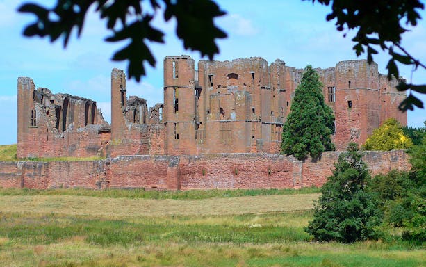 Kenilworth Castle ruins surrounded by greenery in Warwickshire, England.