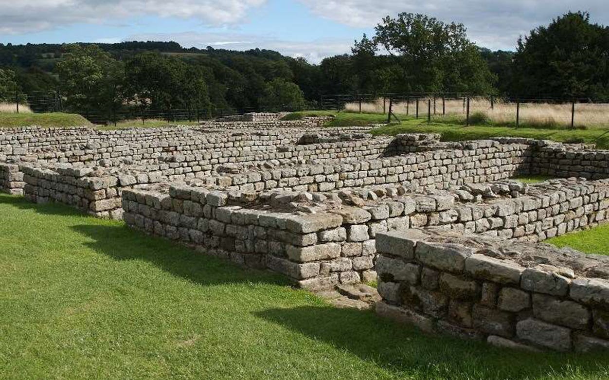 Chesters Roman Fort ruins with stone walls and green landscape in Northumberland, England.