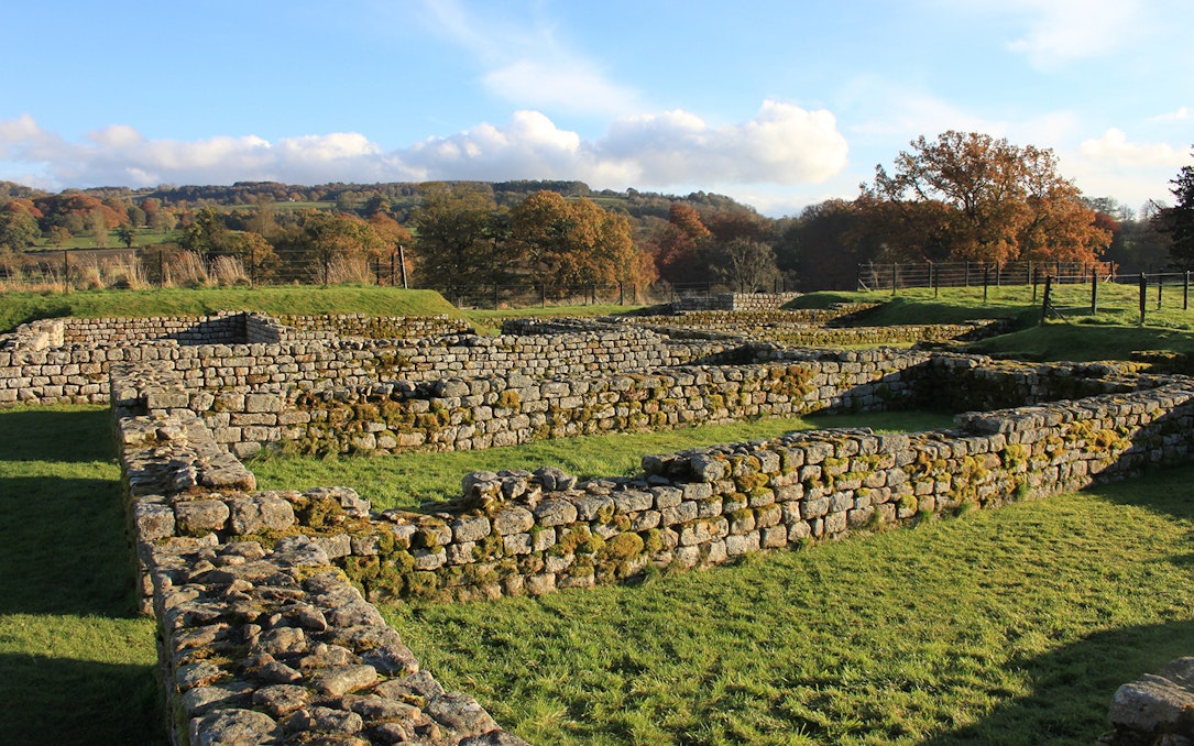 Chesters Roman Fort ruins with stone walls and grassy landscape in Northumberland.