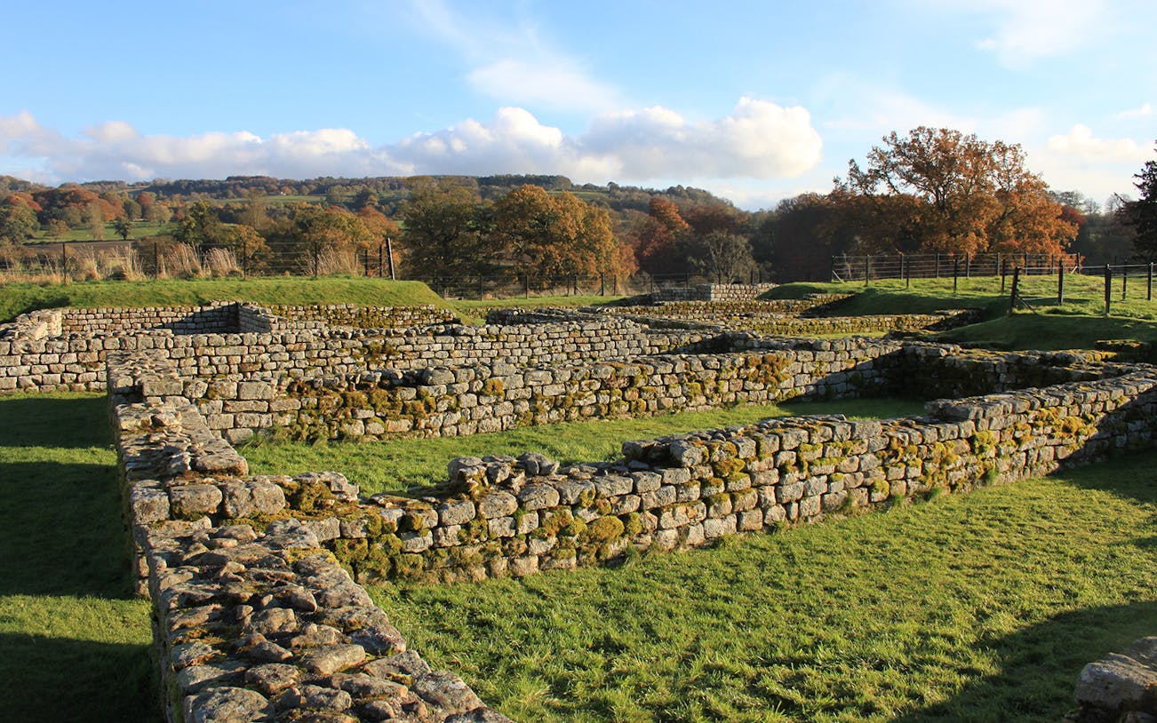 Chesters Roman Fort ruins with stone walls and grassy landscape in Northumberland.