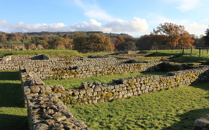 Chesters Roman Fort ruins with stone walls and grassy landscape in Northumberland.