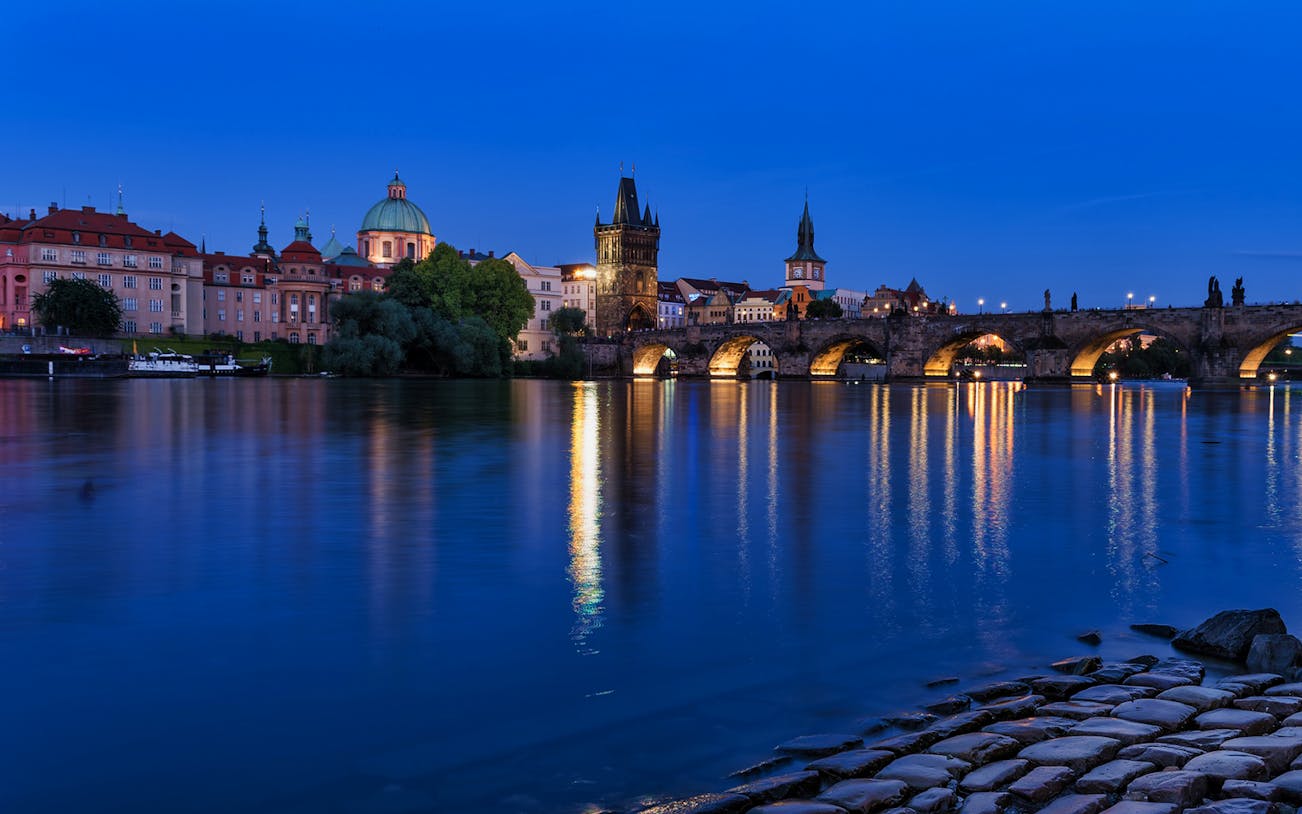 Charles Bridge and Vltava River at night during Prague walking tour.