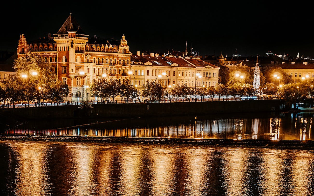 Prague riverside illuminated at night during After Dark Walking Tour.