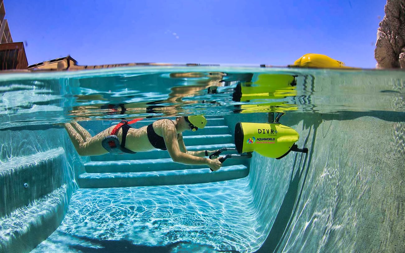 Person using DIVR virtual reality snorkeling device in a pool.