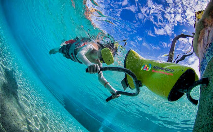 Person using virtual reality headset while snorkeling with underwater scooter.