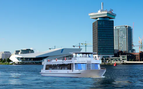 Tour boat cruising in front of A'DAM Tower and EYE Film Museum, Amsterdam Harbor.