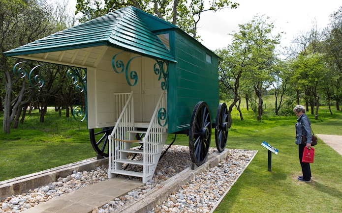 Historic carriage at Osborne House with visitor reading information sign.