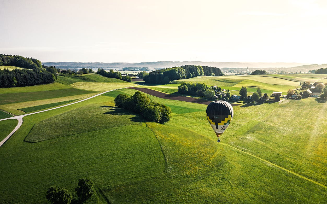Hot-air balloon over green fields near Prague during a scenic tour.