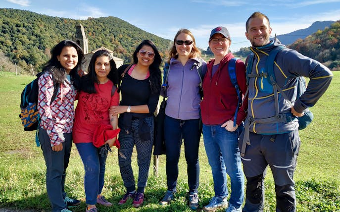 Group of hikers in La Garrotxa Volcanic Zone with medieval village backdrop.
