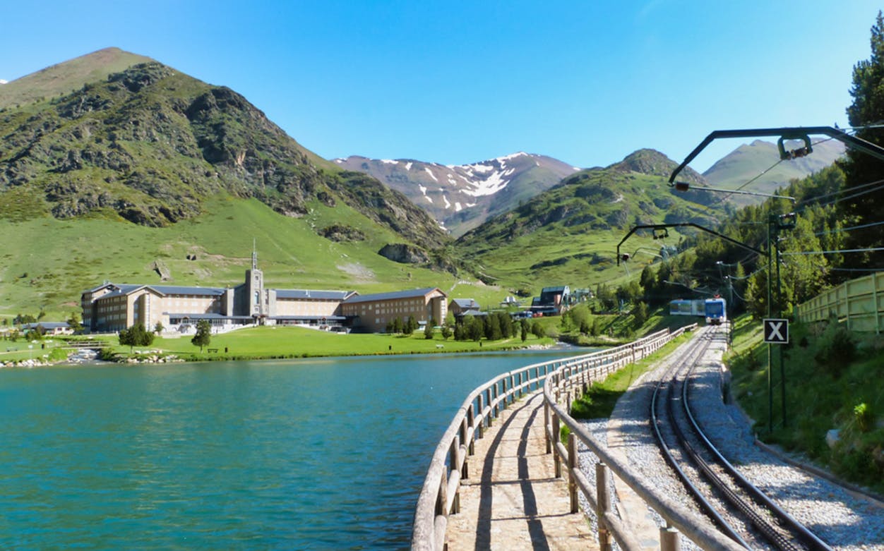 Vall de Núria with mountain backdrop, lake, and train tracks in the Pyrenees.