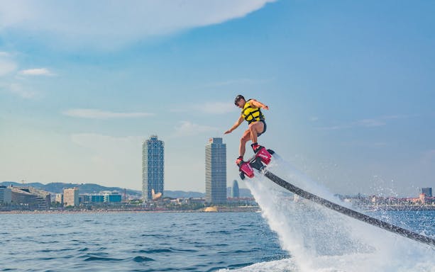 Flyboarding over the sea with Barcelona skyline in the background.