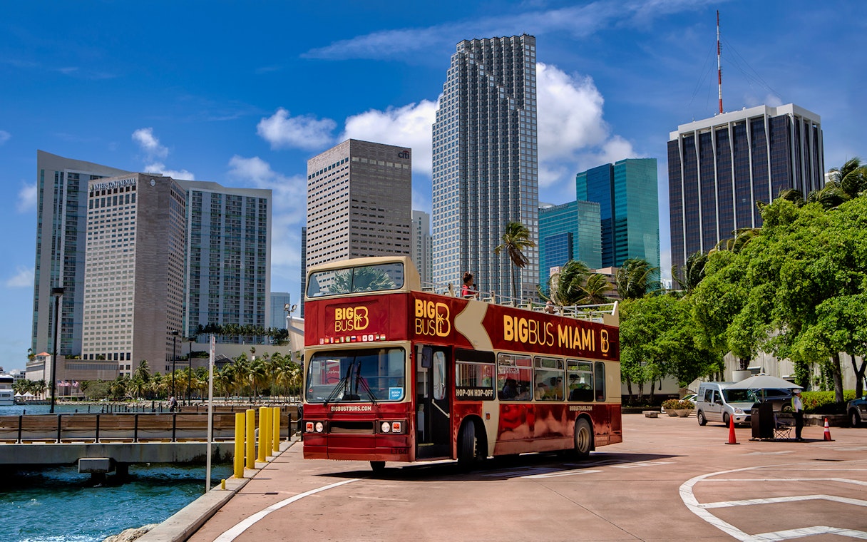 Big Bus Miami tour passing downtown skyscrapers on a sunny day.