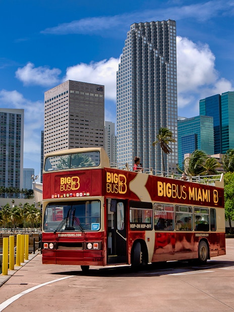 Big Bus Miami tour passing downtown skyscrapers on a sunny day.