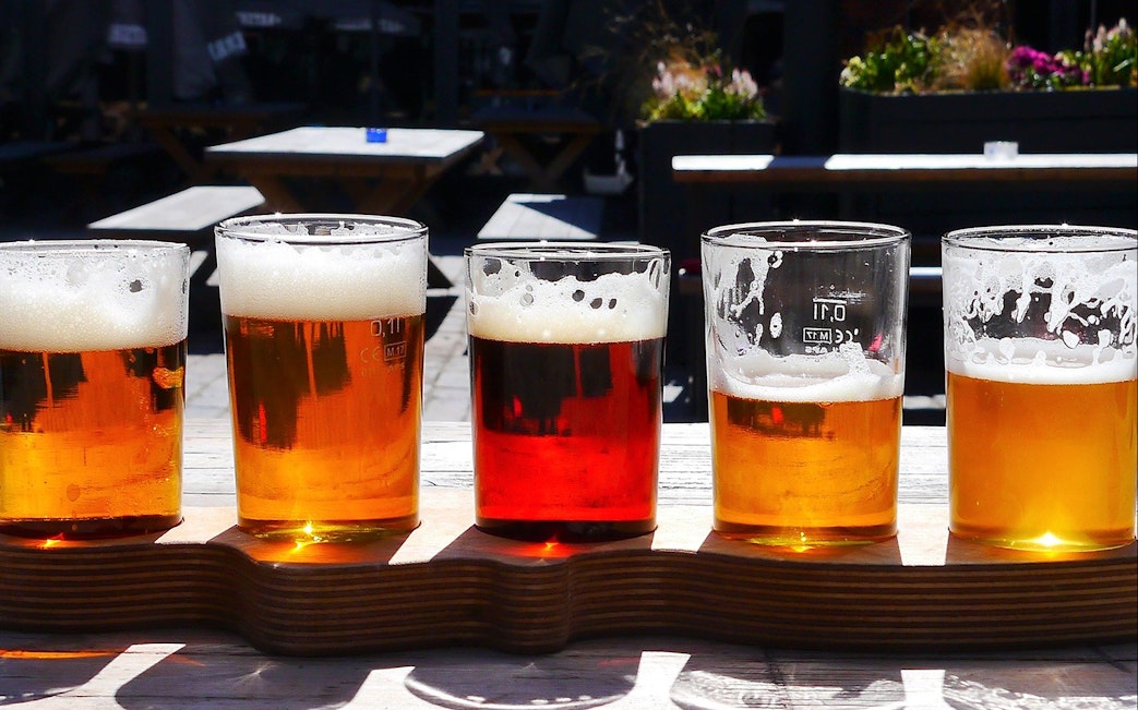 Beer flight with various brews on a wooden tray during a brewery tour with lunch and tasting.