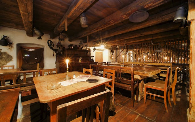 Medieval banquet hall with wooden tables and candlelight ambiance.