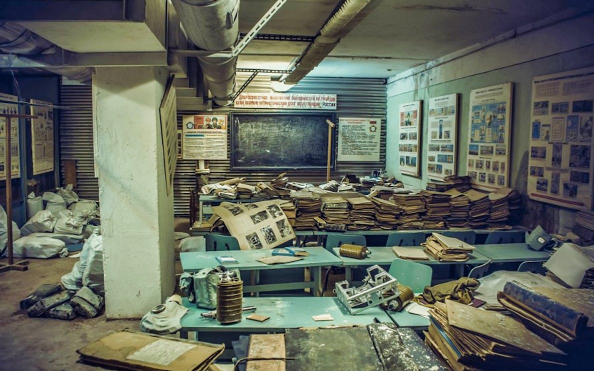 Nuclear bunker interior with old documents and gas masks on tables, part of 3-hour Communism Tour.