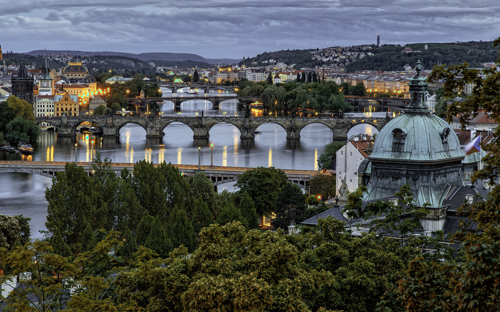 Prague cityscape with Charles Bridge over Vltava River at dusk.