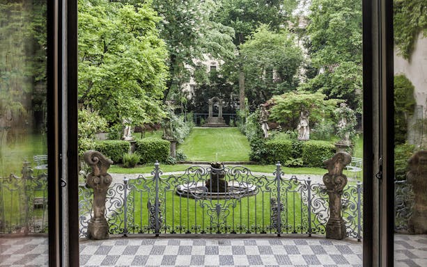 Leonardo's Vineyard garden view with statues and ornate gate in Milan, Italy.