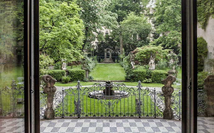 Leonardo's Vineyard garden view with statues and ornate gate in Milan, Italy.