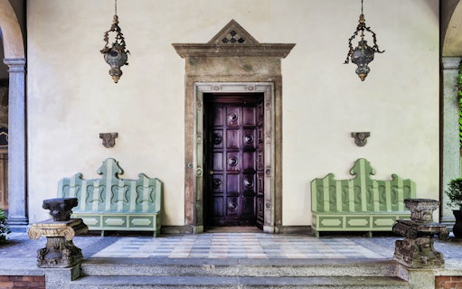 Entrance to Leonardo's Vineyard with ornate door and benches, Milan, Italy.