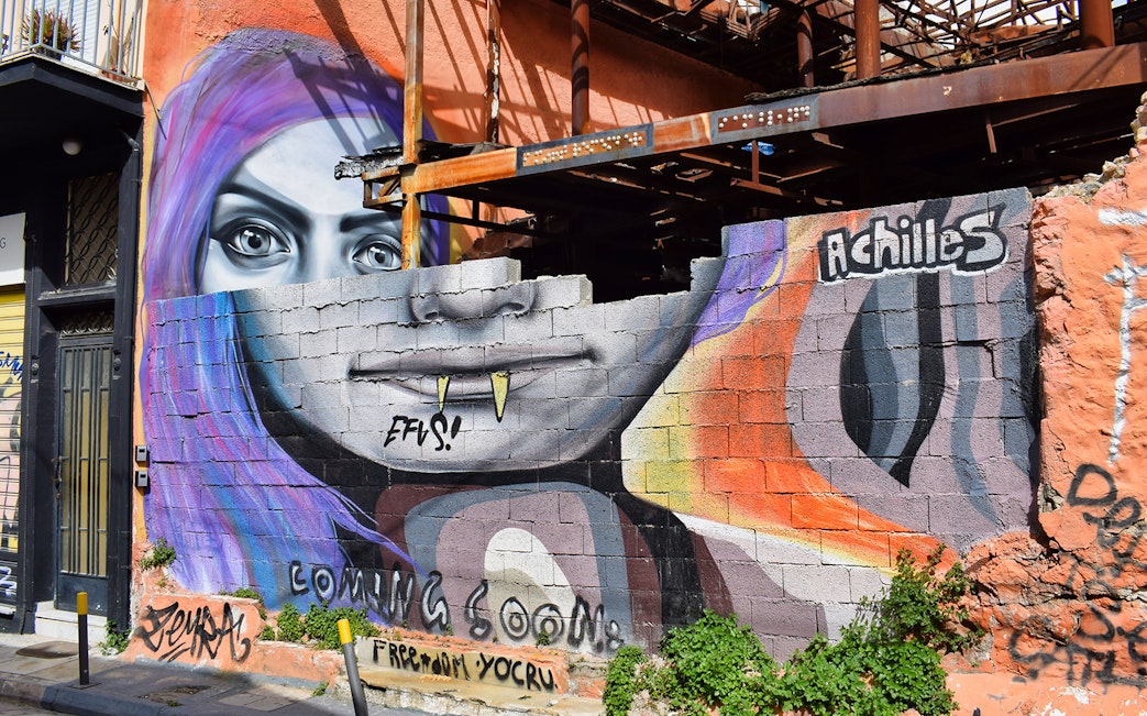 Street art mural featuring a colorful face on a wall in Athens, Greece.