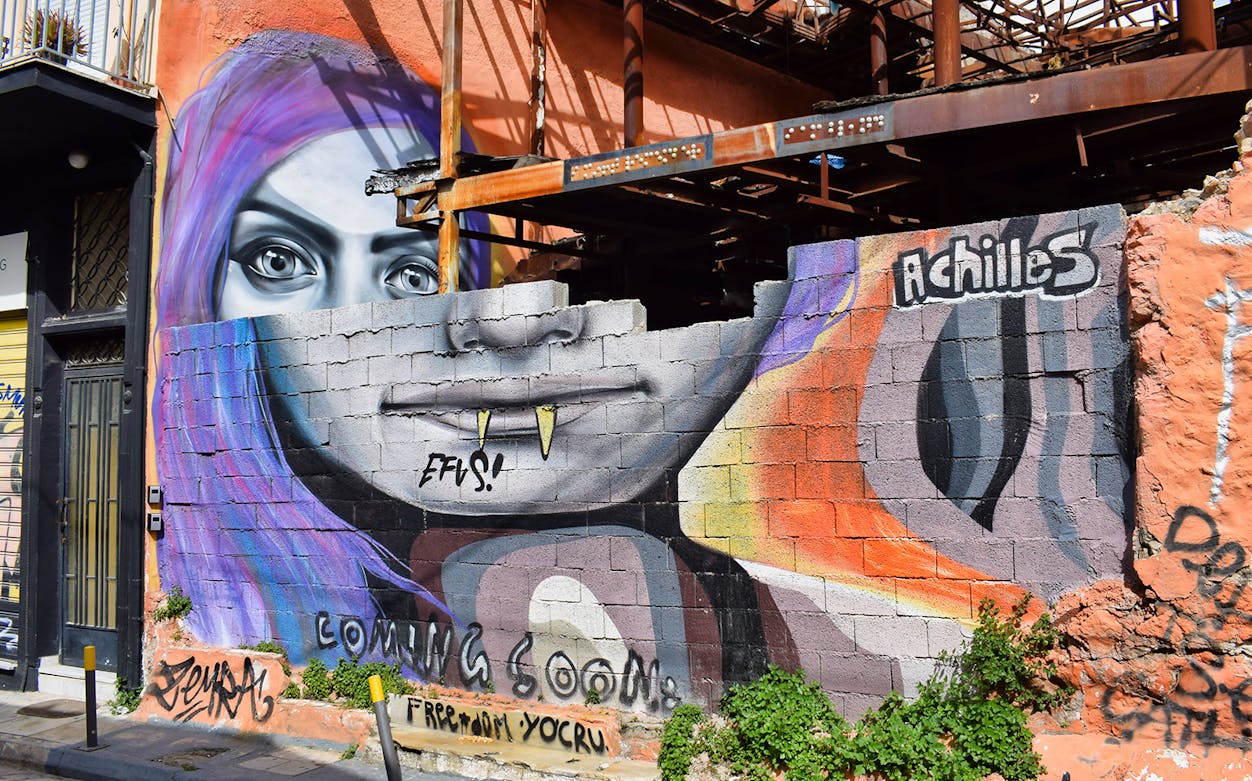 Street art mural featuring a colorful face on a wall in Athens, Greece.