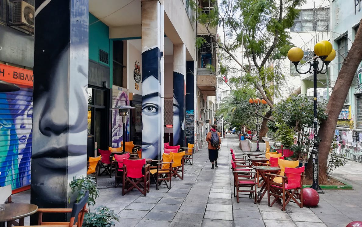 Street art and colorful café chairs in Exarcheia, Athens, during a walking tour.