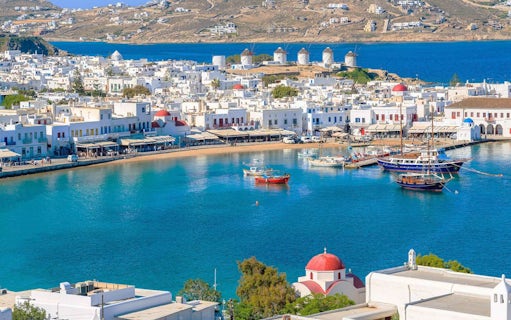 Mykonos harbor with boats and iconic windmills in the background during a 4-hour island cruise.