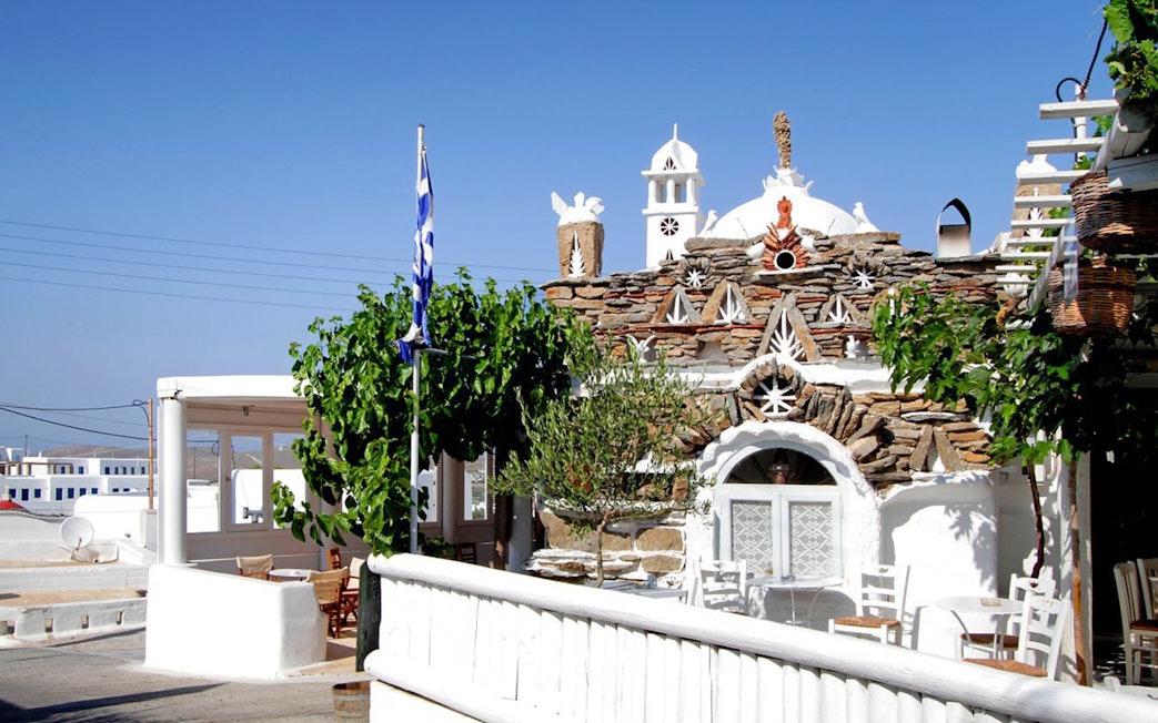 Traditional Mykonos architecture with Greek flag on a sunny day.