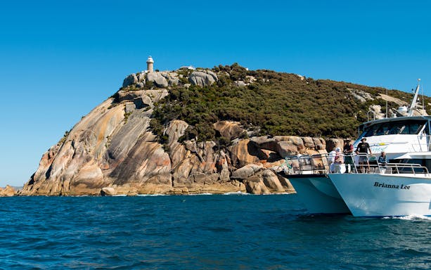 Cruise boat near Wilsons Promontory lighthouse on a sunny day.