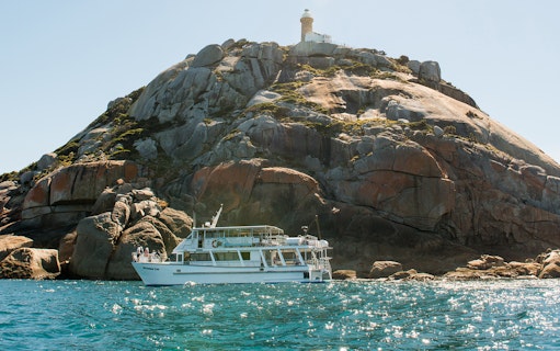 Cruise boat near rocky island with lighthouse at Wilsons Promontory.