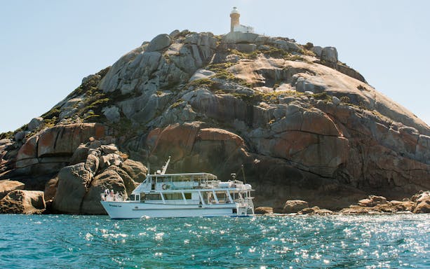 Cruise boat near rocky island with lighthouse at Wilsons Promontory.